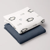 Penguin muslin swaddle and navy 4-ply blanket folded in a neat stack